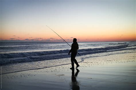Silhouette Of Person Surf Fishing Alone On Ocean Beach With Long Rod