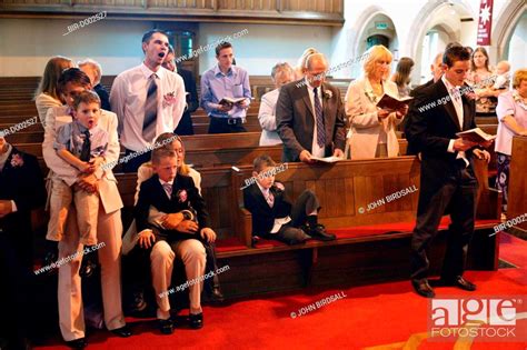 Wedding Guests Standing In Church Pews Singing Hymn Stock Photo