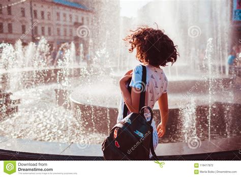 Happy Young Woman Running And Dancing By Fountain On