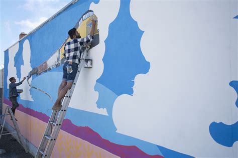 Two Men Are Painting The Side Of A Building
