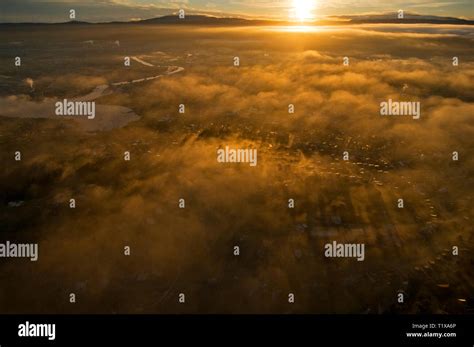Aerial Image Of Orange Dawn Sunlight Shining Through River Ground Mist