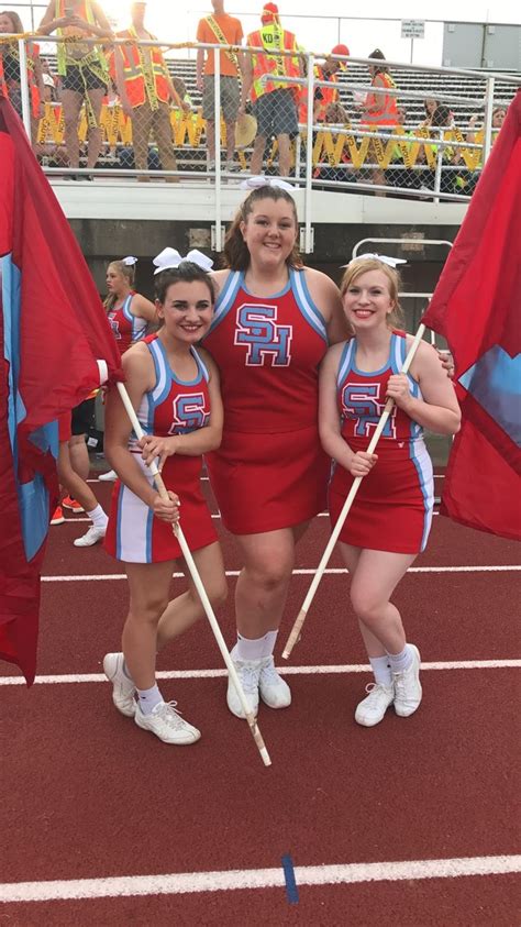 The Cheerleaders Are Posing For A Photo With Their Sticks And Flags In Hand
