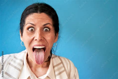 mature woman sticking out tongue in front of blue wall stock foto adobe stock