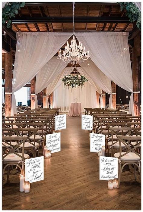 An Indoor Wedding Venue With White Drapes And Chandelier Hanging From