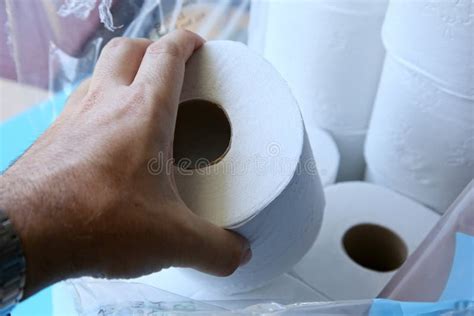Closeup Shot Of A Person Holding A Roll Of Toilet Paper Over A Pile Of