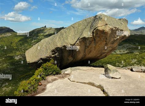 A Huge Granite Monolith Hangs On The Edge Of A High Cliff Overlooking A