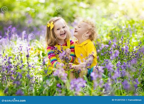 Kids Playing In Blooming Garden With Bluebell Flowers Stock Image