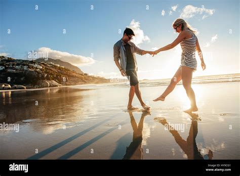 Beautiful Young Couple Holding Hands And Playing On The Shore Happy