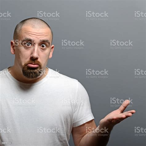 Portrait Of A Confused Man Against Gray Background Stock Photo