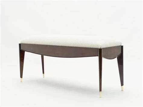 An Upholstered Bench With Wooden Legs And A White Cushion On The Backrest
