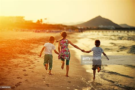 Brothers And Sister Running On Beach On Sunset Photo Getty Images