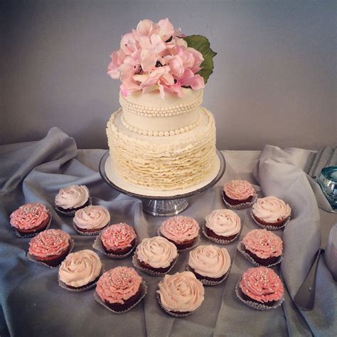 A Table Topped With Lots Of Cupcakes Next To A White And Pink Cake