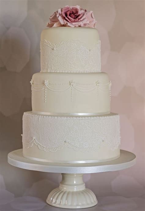 A Three Tiered White Wedding Cake With A Pink Flower On Top