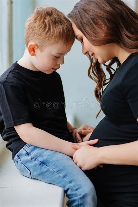 A Pregnant Mother And Son In Black Clothes By The Window Stock Image