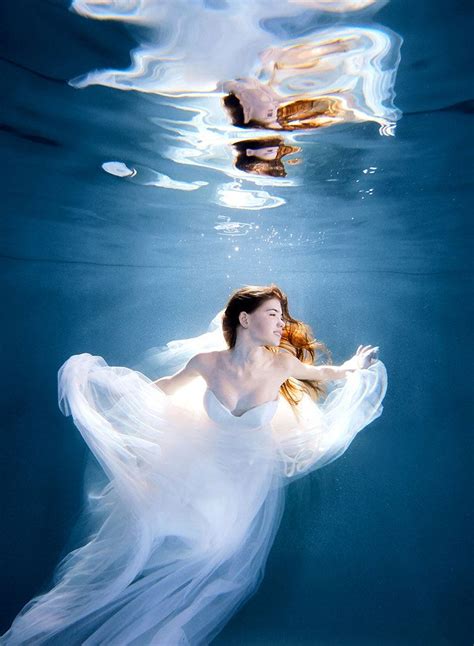 A Woman In A White Dress Swimming Under Water