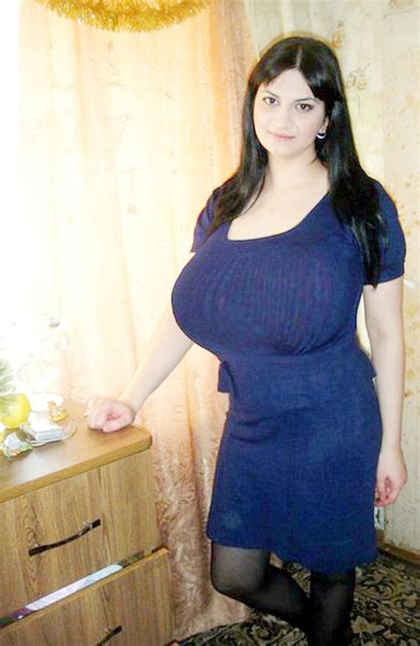 A Woman In A Blue Dress Is Standing Near A Dresser With Glasses On It