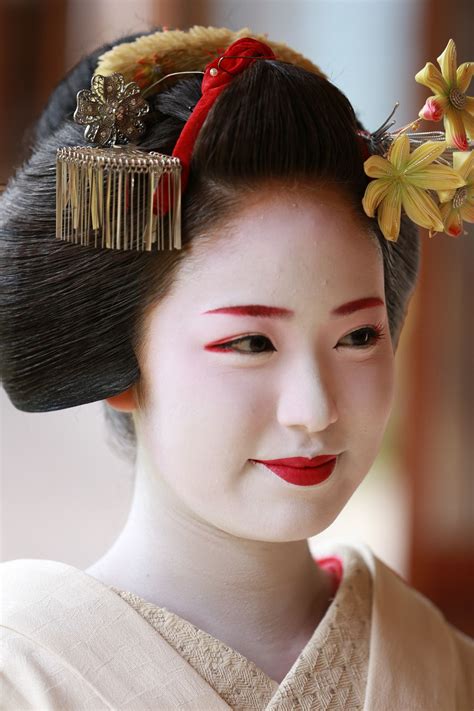 A Geisha Woman In Traditional Japanese Dress And Hair Comb With Flowers