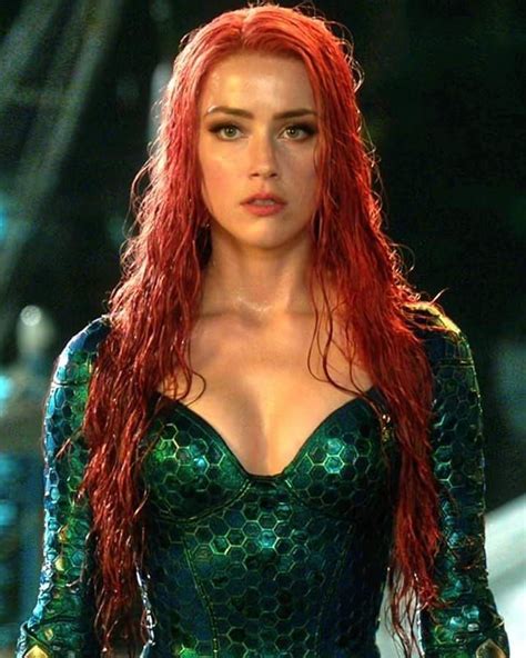 A Woman With Long Red Hair Standing Next To A Body Of Water At Night