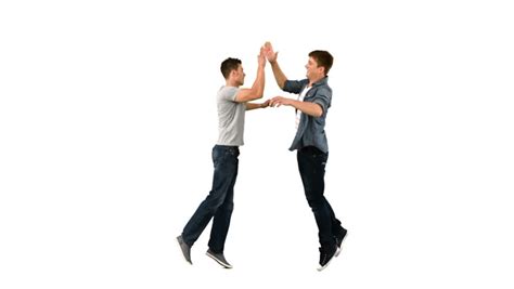 Two Guys High Fiving One Another In Slow Motion Against A White