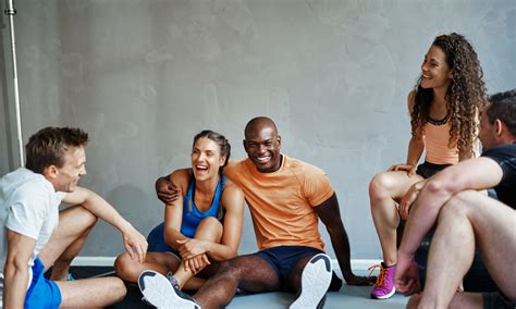 Diverse Friends In Sportswear Sitting Together In A Gym Laughing
