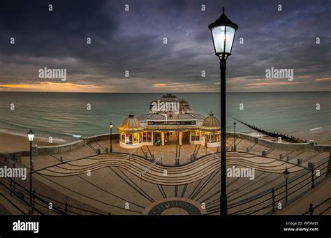The Street Lights Start To Come On As The Sun Sets At Cromer Pier Stock