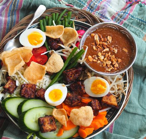 Gado gado definition, an indonesian dish consisting of raw or slightly cooked vegetables, as green beans, bean sprouts, and cabbage, with baked or boiled potatoes, served with a spicy peanut, chile, and coconut milk sauce. Gado gado met een heerlijke pindasaus - metzkooktover