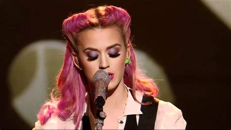 a woman with pink hair singing into a microphone