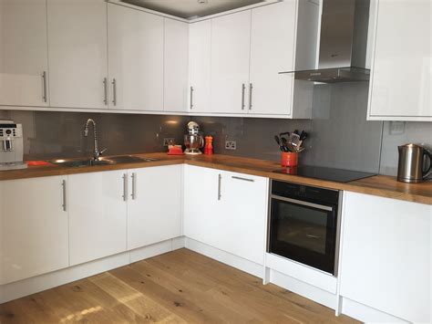 The kitchen worktop is also a working area. White gloss kitchen and grey glass splashbacks | White ...
