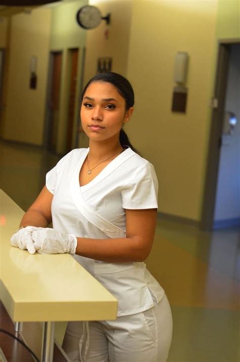 a woman in white scrubs her hands on a counter top while standing next to a hospital hallway