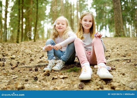 Two Cute Young Sisters Having Fun During Forest Hike On Beautiful Early Spring Day Active