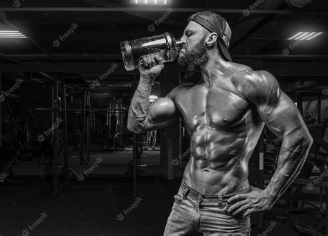 Premium Photo Muscular Man In The Gym Drinks From A Huge Bottle