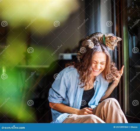 Beautiful Young Woman Laughing Happily With A Cat On Her Head