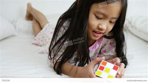 4k Video Little Asian Girls Playing Rubik Cube On The Bed Stock Video