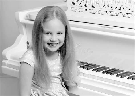 Beautiful Little Girl Is Playing On A White Grand Piano Stock Image