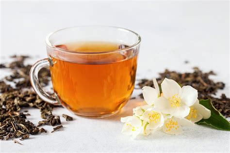 Green tea with jasmine in cup and teapot on wooden table on green background. 11 Health Benefits of Jasmine Tea (and Side Effects ...