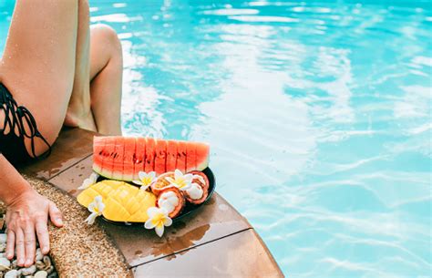 Woman Weared Swimsuit Sitting On Swimming Pool Side With Plate Of