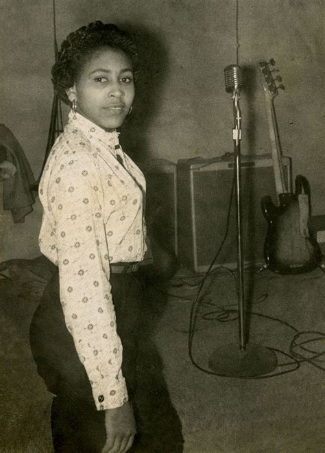 A Black And White Photo Of A Woman Standing In Front Of A Recording