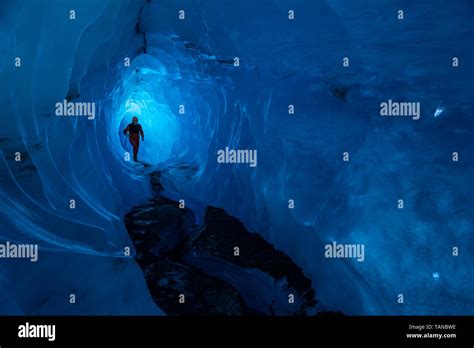 A Guide Walks Through The Tunnel Of A Glacier Ice Cave On The Matanuska