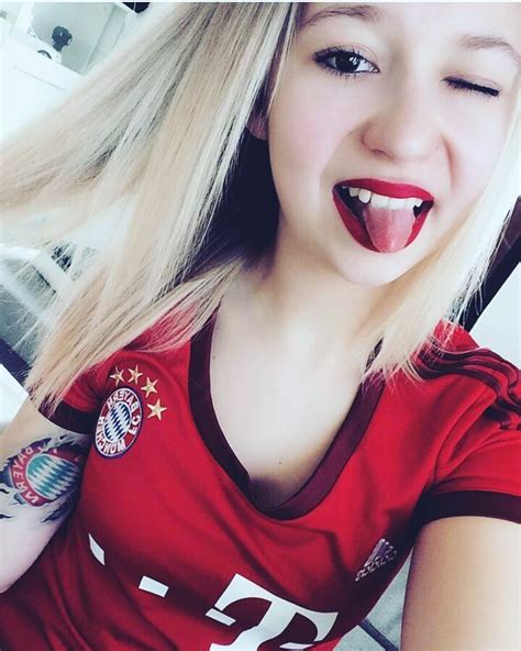 A Woman With Long Blonde Hair Sticking Out Her Tongue And Wearing A Red Tshirt