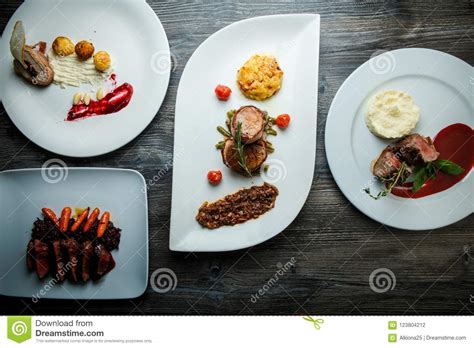 Wooden Table Topped With White Plates With Different Types Of Food In