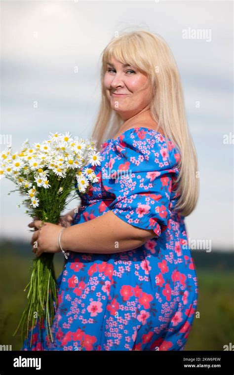 beautiful plus size woman with white hair in a summer dress posing outdoors with daisies chubby