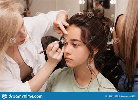 Shooting In A Beauty Salon A Makeup Artist Does Eyebrow Styling For A Young Dark Haired Girl