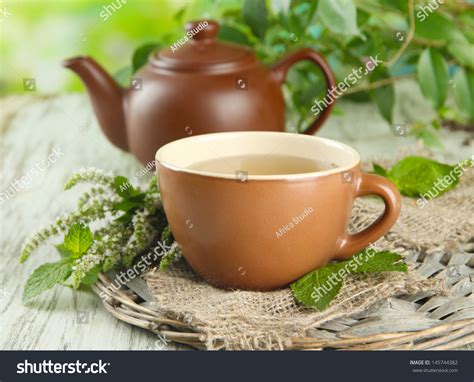 Teapot And Cup Of Herbal Tea With Fresh Mint Flowers On Wooden Table