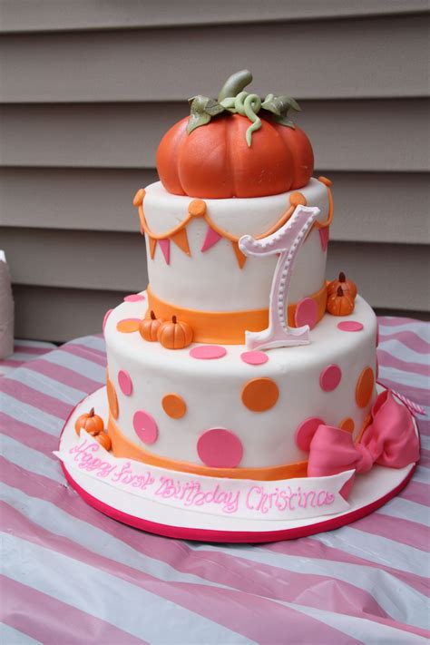 A Three Tiered Birthday Cake With Polka Dots And A Pumpkin On Top Is