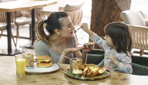 Mamá Con Una Linda Hija Comiendo Comida Rápida En Un Café Foto Gratis