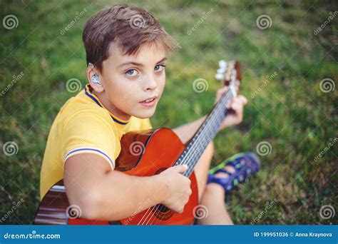 Hard Of Hearing Preteen Boy Playing Guitar Outdoors Child With Hearing