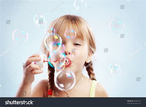 Portrait Of Funny Lovely Little Girl Blowing Soap Bubbles Stock Photo