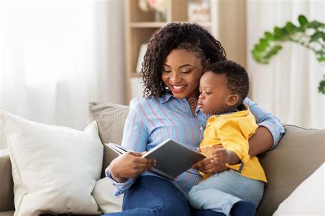 African American Mother With Book And Baby At Home Stock Photo Image