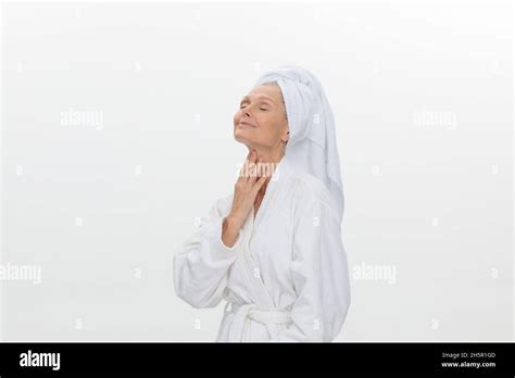 a beautiful mature woman wearing a white bathrobe and a towel wrapped around her head stock