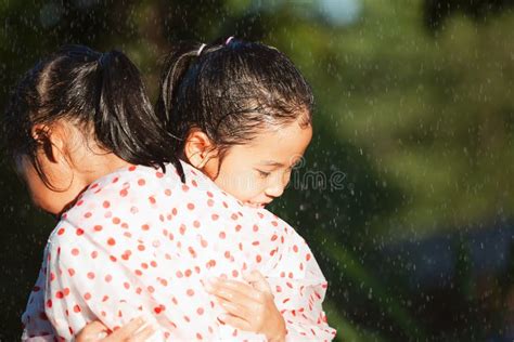 Two Asian Child Girls Wearing Raincoat Hugging Each Other In The Rainy